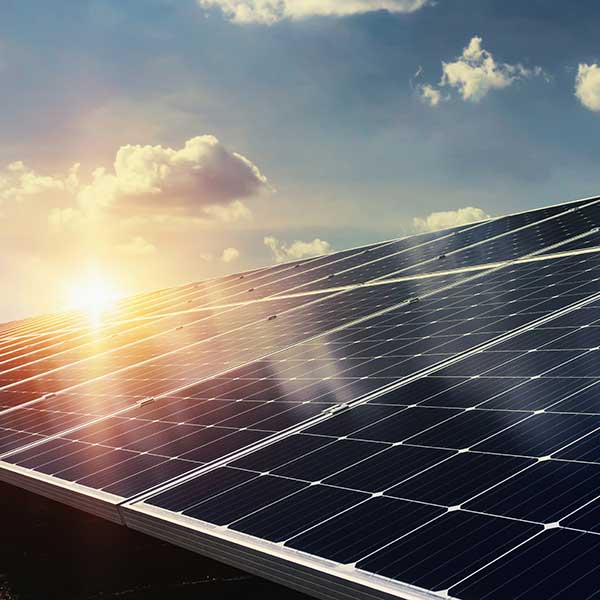 Un lever de soleil se reflète sur des panneaux solaires installés sur un toit.