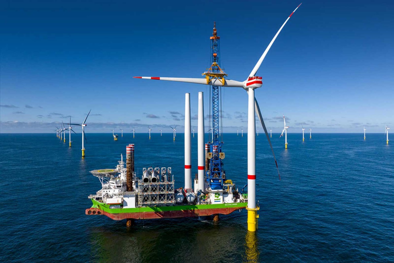 Un navire d'installation d'éoliennes avec des grues et des turbines dans l'océan, entouré de plusieurs éoliennes.
