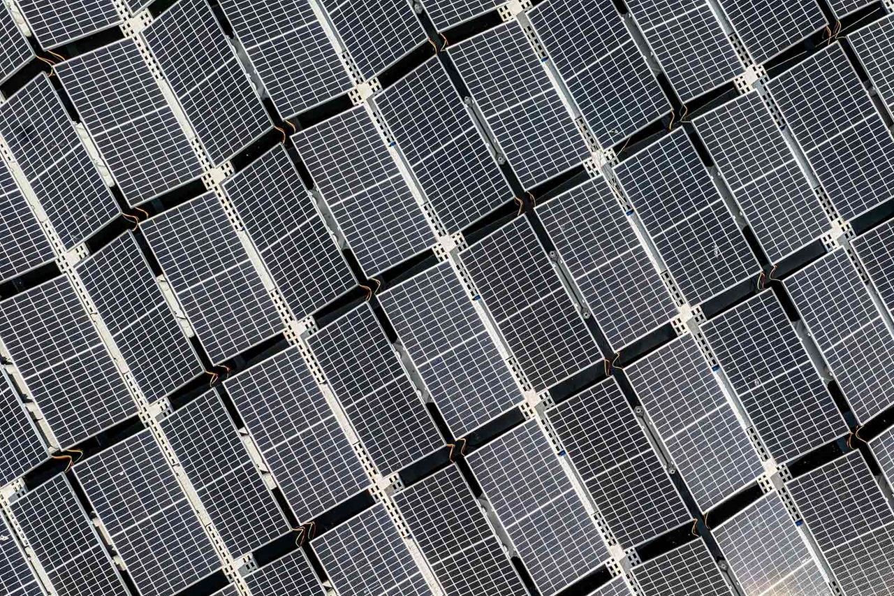Aerial view of multiple solar panels arranged in a grid, showcasing their reflective surfaces.