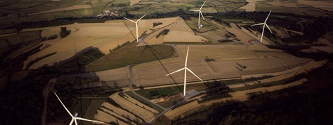 Vue aérienne d'un paysage rural avec plusieurs éoliennes au milieu de champs et de parcelles d'arbres.