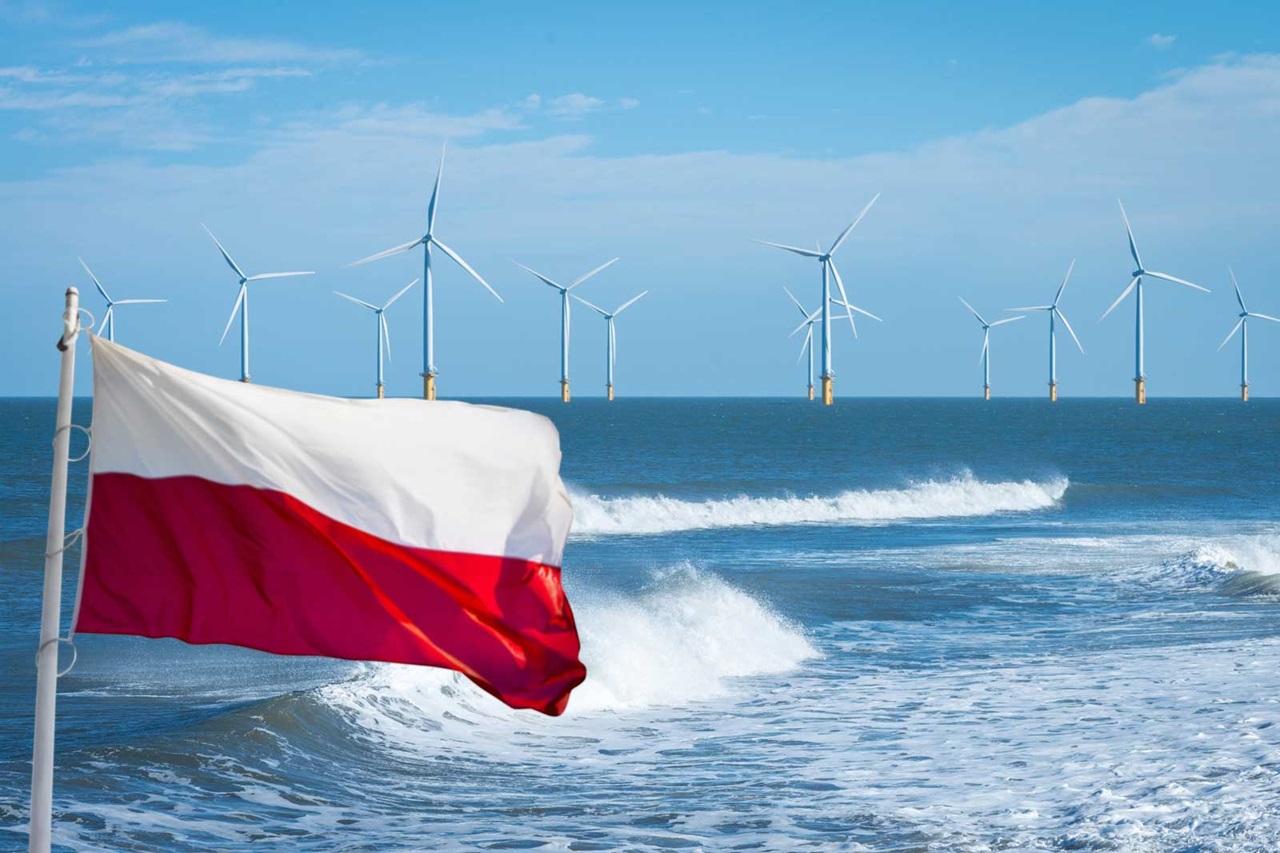The Polish flag waves in the foreground, while wind turbines are visible in the background over the sea.