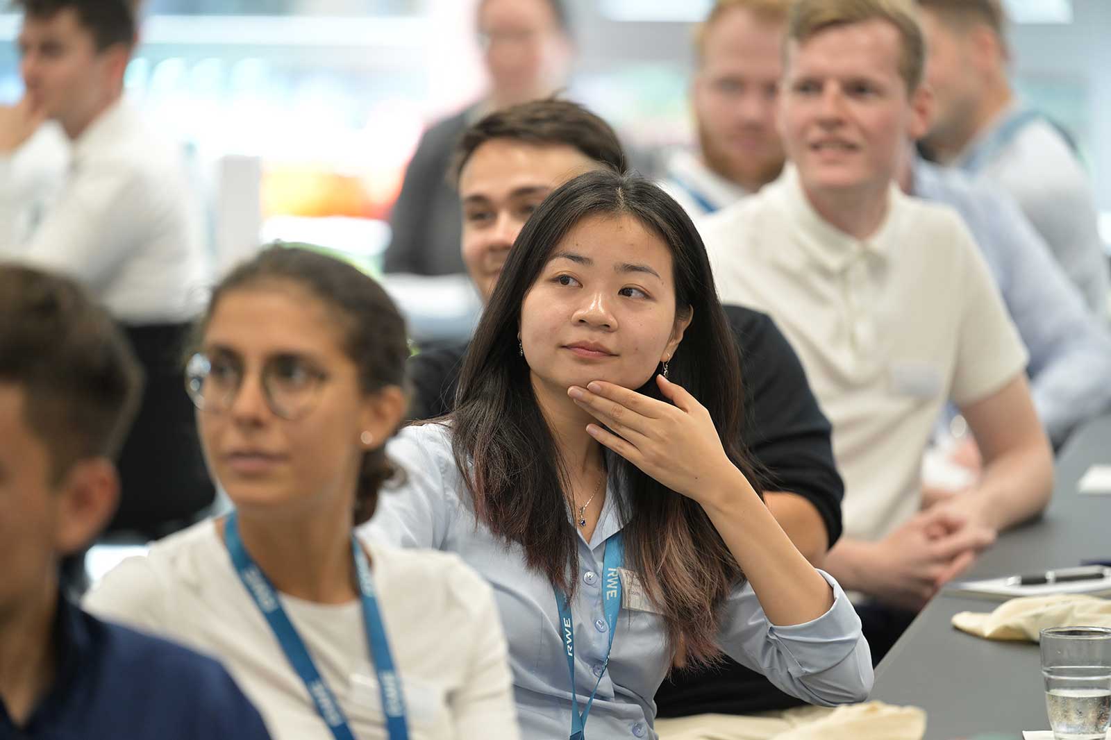A group of people attentively listening at an event. Some are wearing name badges.